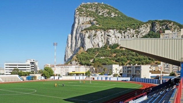 The Rock of Gibraltar overlooks Victoria Stadium, which cannot be used due to its artificial turf. (uefa.com)